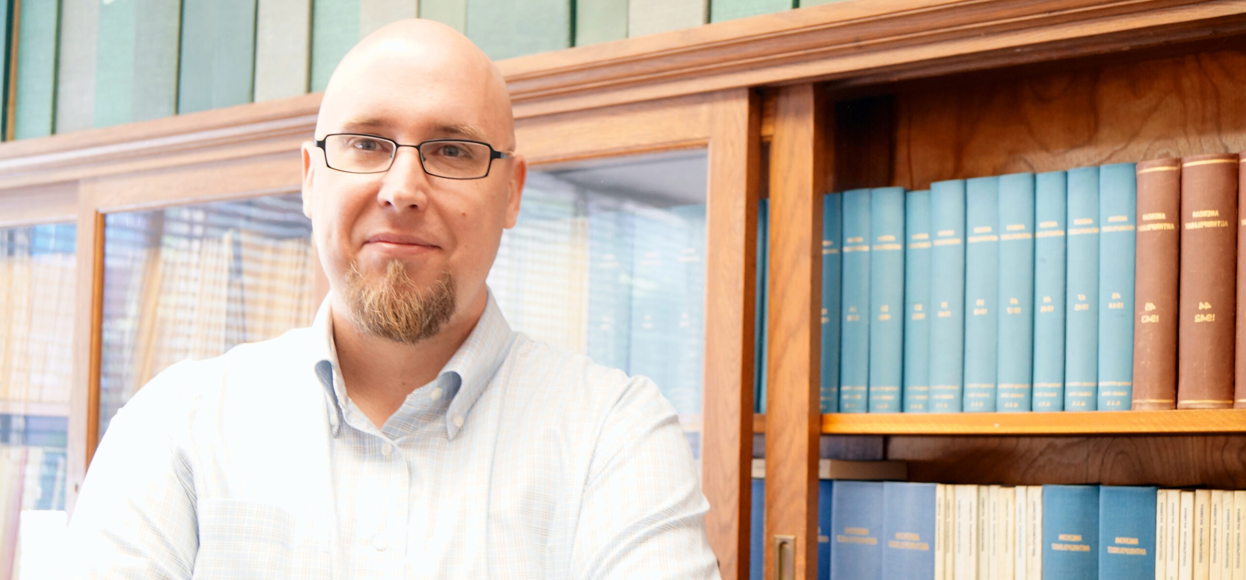 dr watrall in front of a book case